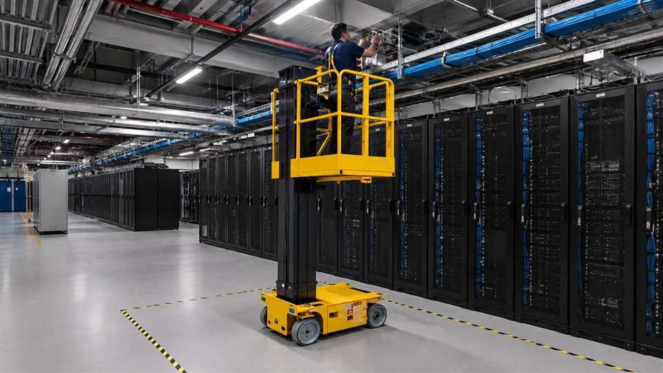 Compact lift platform inspecting cooling sensors and fiber trays in a completed data hall